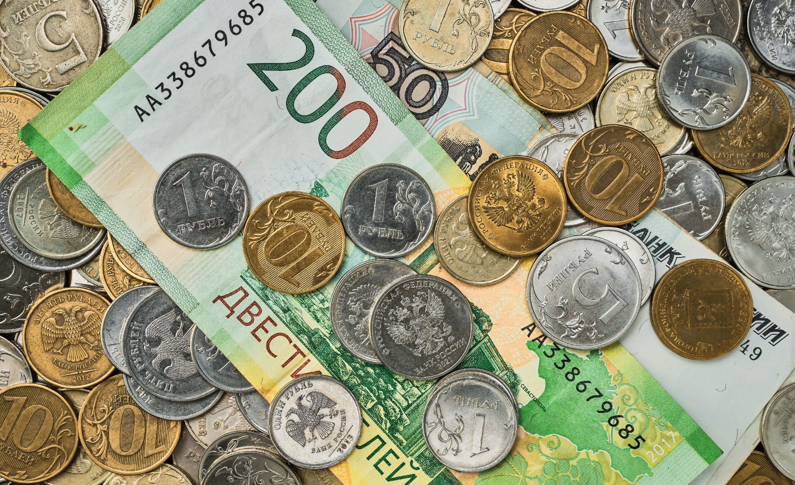 money coins banknotes russian rubles scattered heap table top view idea background banner market news 1 scaled Названа огромная сумма наличных в триллионах рублей, которые россияне хранят «под матрасом»