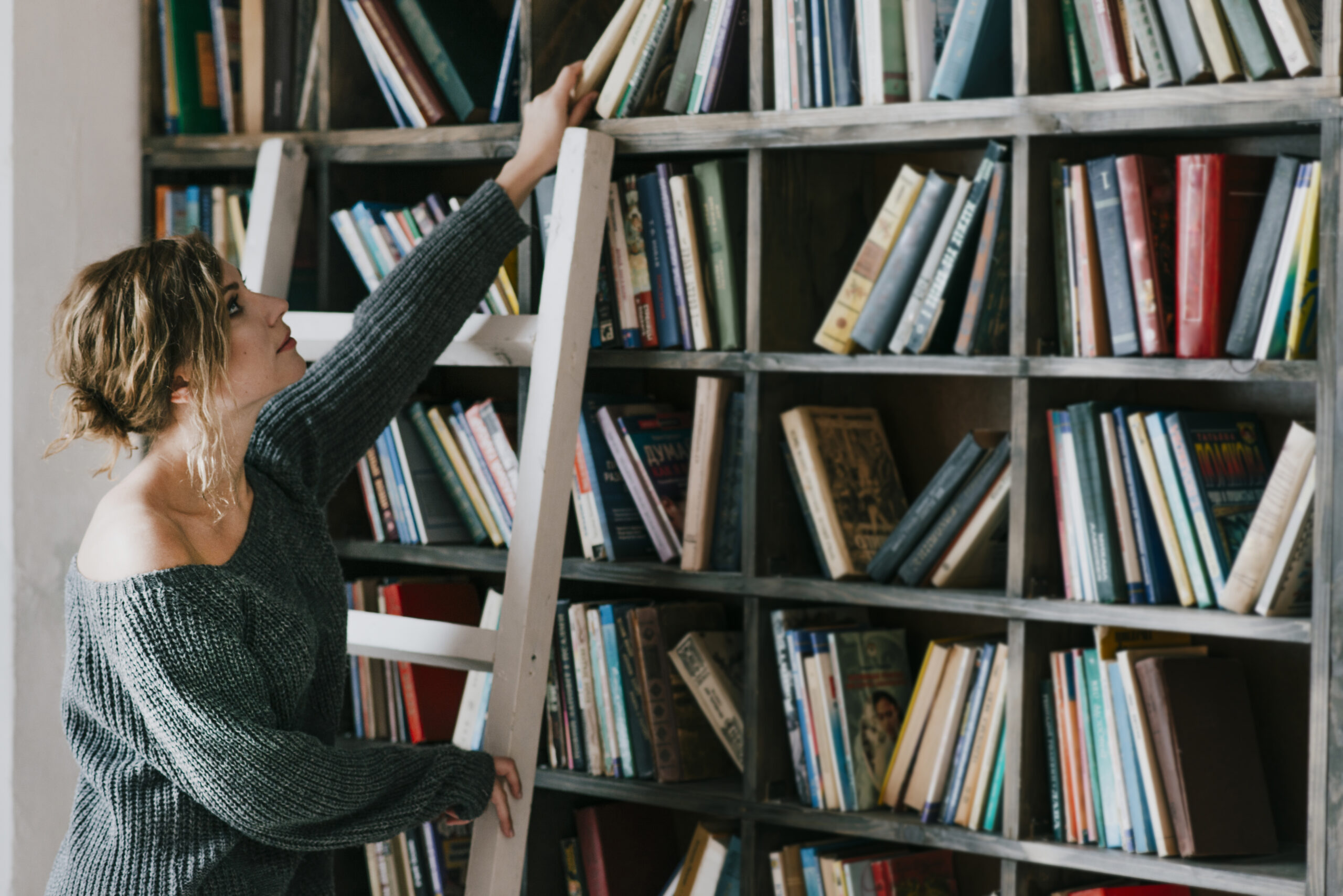 woman ladder taking book scaled В Рузаевке модельная библиотека стала центром образования для детей