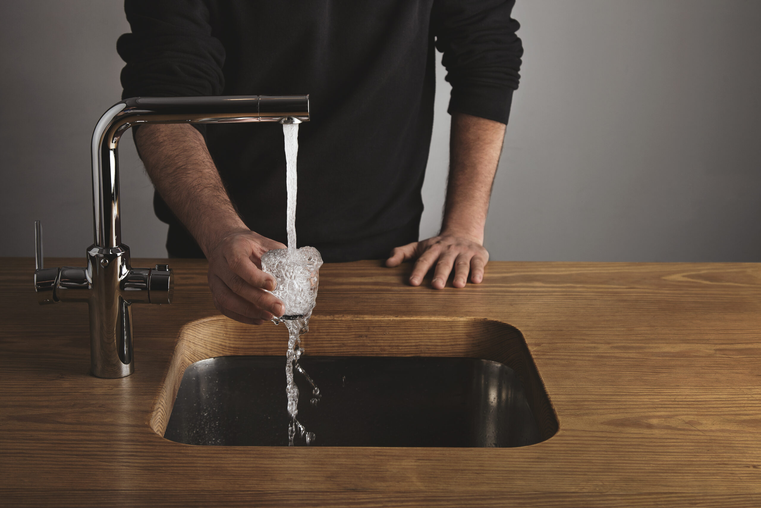 brutal barista black sweatshot thick wooden table rinses small tranparent glass with water silver metal tap cafe shop water drops out glass scaled Часть Саранска останется сегодня без воды