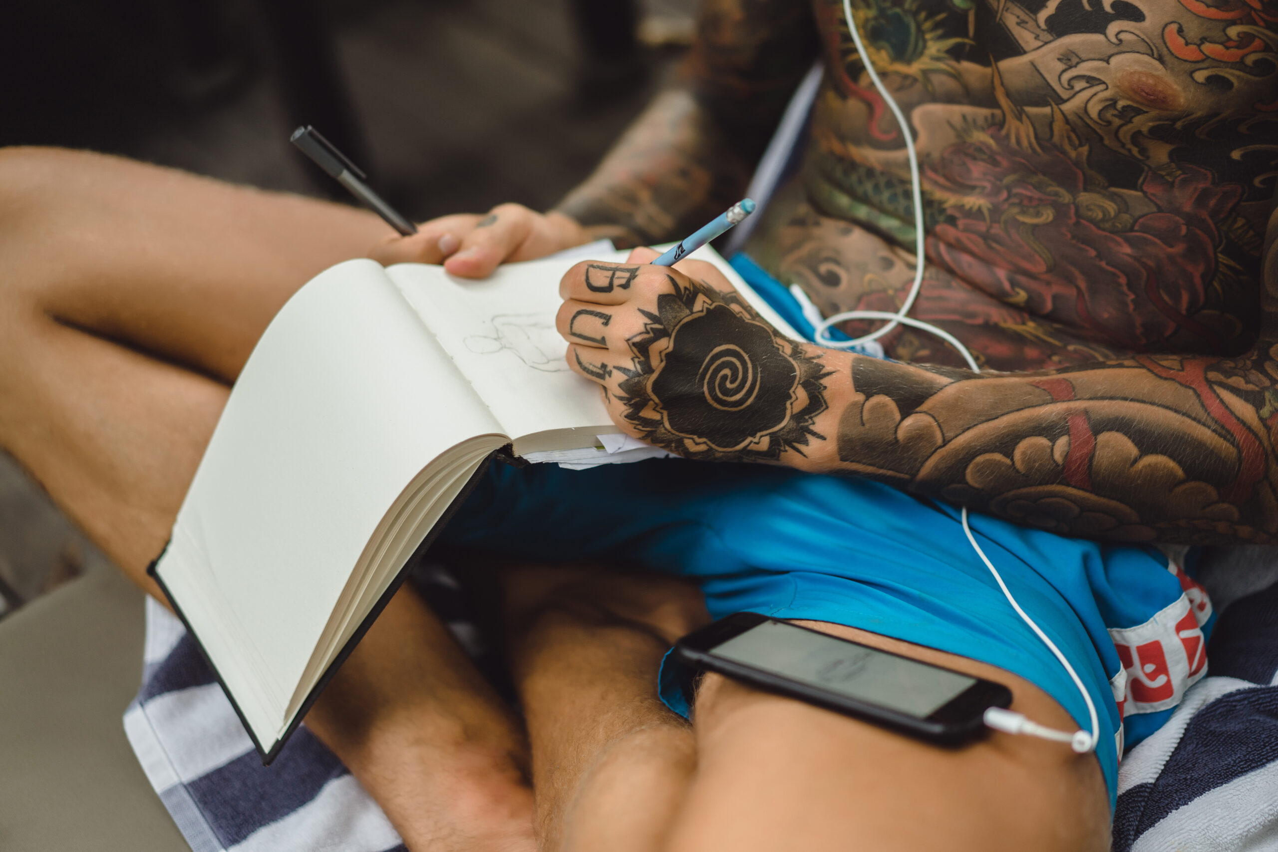 young man tattoos wearing headphones listens music draws notebook scaled Житель Саранска лишился 6 тысяч за размещение татуировки в интернете